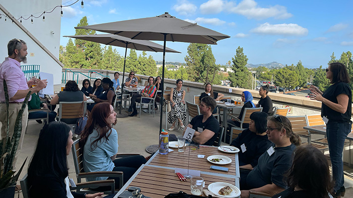 Participants seated outdoors at a MCTEN Workshop, engaging in discussion under umbrellas with scenic views in the background.